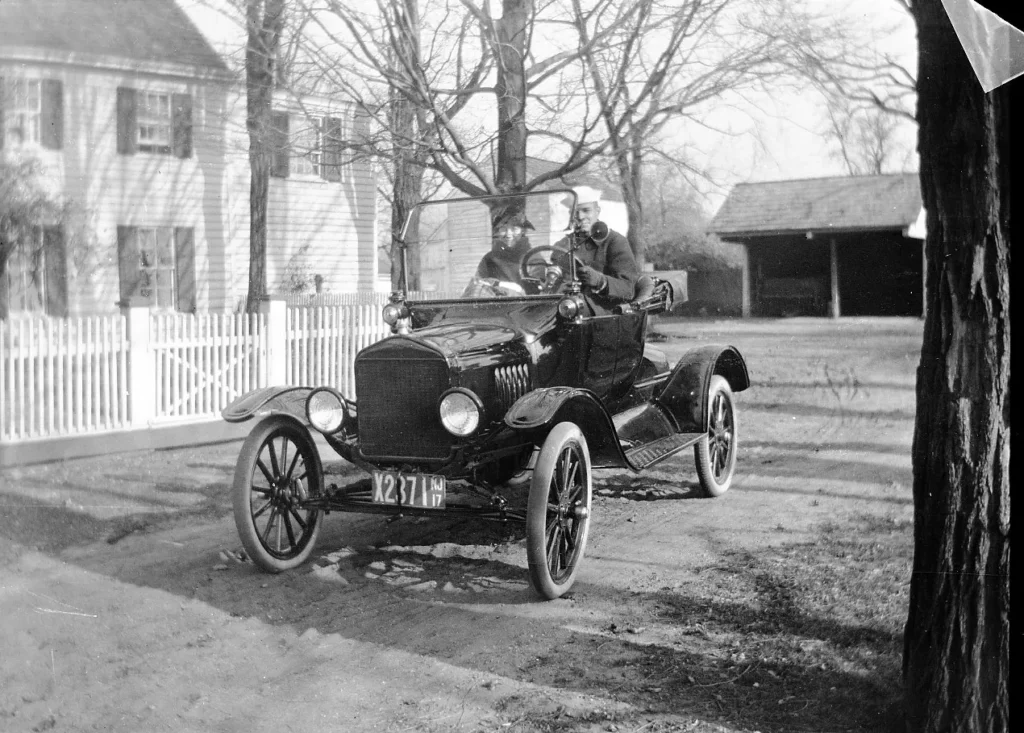 Black-and-white photograph of a Ford Model T parked near a house, used to frame the fear of being replaced by AI.