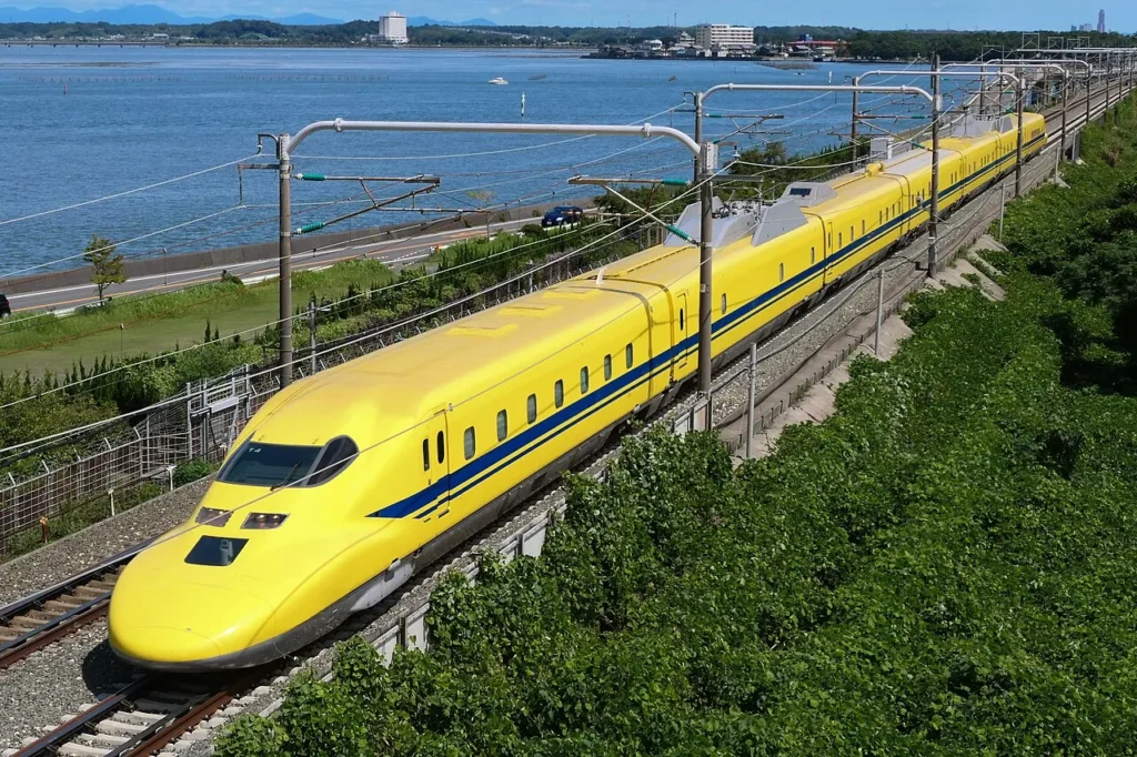 ellow Shinkansen test train on railway tracks, illustrating domain mapping between engineering and biological solutions.